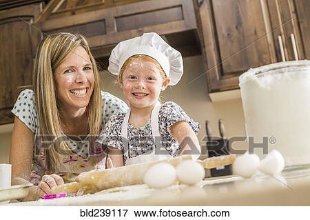 Stock Photo - Caucasian mother and daughter covered in flour from food fight. Fotosearch