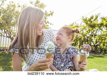 Stock Image - Caucasian mother and daughter eating ice cream cones. Fotosearch