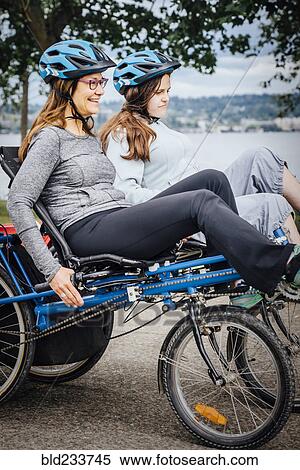 Stock Photography - Caucasian mother and daughter riding tandem bicycle. Fotosearch