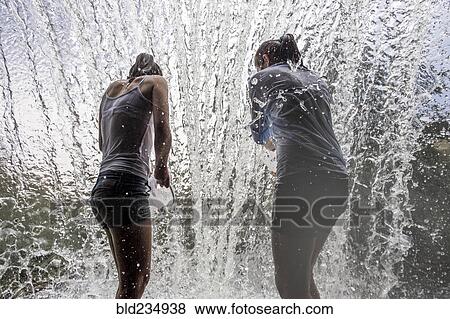 Stock Photo - Caucasian mother and daughter standing in waterfall. Fotosearch