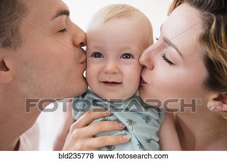 Stock Photo - Caucasian mother and father kissing cheeks of baby son. Fotosearch
