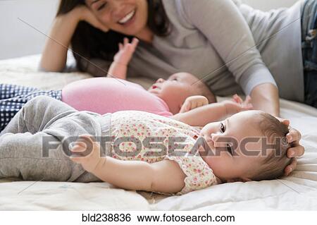 Caucasian mother caressing head of baby daughter on bed View Large Photo Image Stock Photograph - Caucasian mother caressing head of baby daughter on bed. Fotosearch