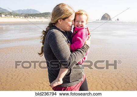Caucasian mother carrying daughter on beach View Large Photo Image Picture - Caucasian mother carrying daughter on beach. Fotosearch