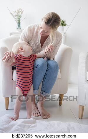 Stock Photography - Caucasian mother helping standing baby son. Fotosearch