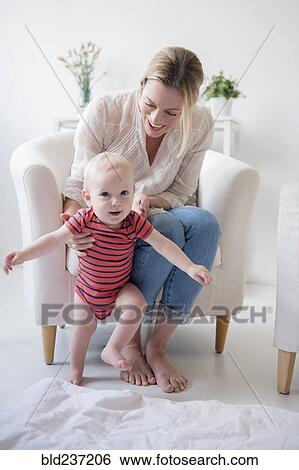 Stock Photograph - Caucasian mother helping walking baby son. Fotosearch