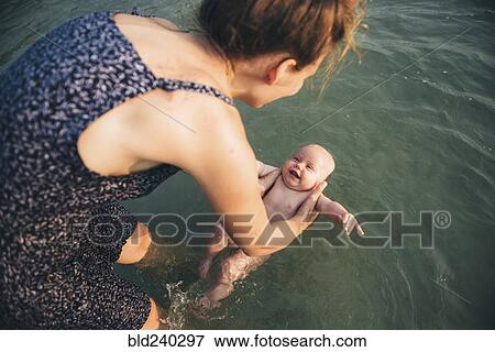 Caucasian mother holding baby daughter in ocean View Large Photo Image Stock Photo - Caucasian mother holding baby daughter in ocean. Fotosearch