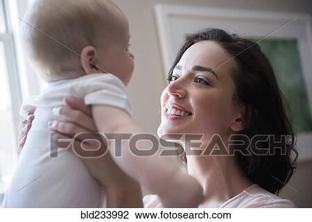 Caucasian mother holding baby son face to face View Large Photo Image Stock Image - Caucasian mother holding baby son face to face. Fotosearch
