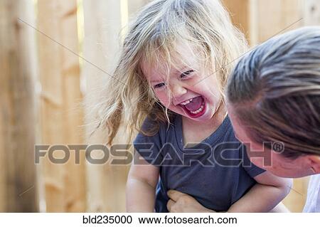 Caucasian mother holding laughing baby daughter View Large Photo Image Stock Image - Caucasian mother holding laughing baby daughter. Fotosearch