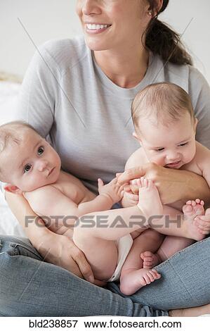Caucasian mother holding twin baby daughters in lap View Large Photo Image Stock Photo - Caucasian mother holding twin baby daughters in lap. Fotosearch