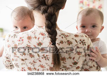 Stock Photo - Caucasian mother holding twin baby daughters. Fotosearch