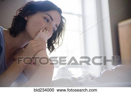 Caucasian mother kissing foot of baby son on bed View Large Photo Image Stock Image - Caucasian mother kissing foot of baby son on bed. Fotosearch