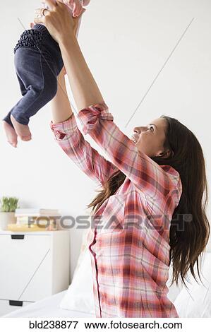 Stock Photo - Caucasian mother lifting baby daughter. Fotosearch