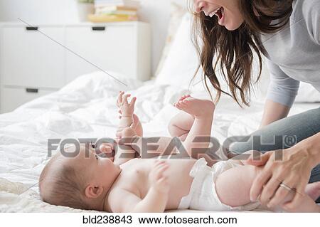 Caucasian mother playing with twin baby daughters on bed View Large Photo Image Stock Image - Caucasian mother playing with twin baby daughters on bed. Fotosearch