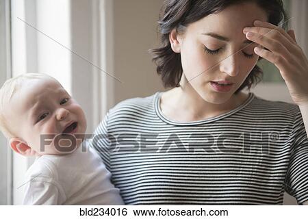 Caucasian mother rubbing forehead while holding baby son View Large Photo Image Stock Photograph - Caucasian mother rubbing forehead while holding baby son. Fotosearch