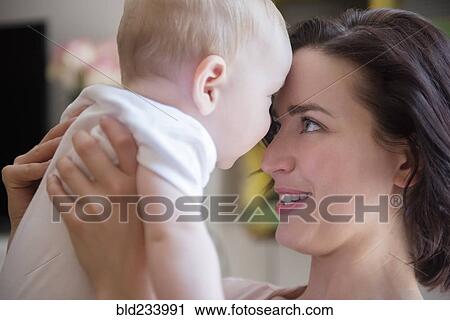 Stock Image - Caucasian mother touching foreheads with baby son. Fotosearch