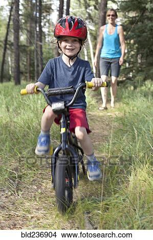 Caucasian mother watching smiling son on bicycle View Large Photo Image Picture - Caucasian mother watching smiling son on bicycle. Fotosearch