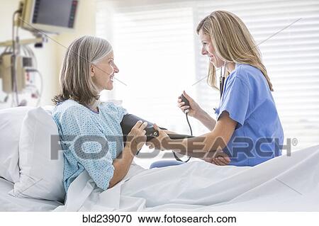 Caucasian nurse measuring blood pressure of woman in hospital bed View Large Photo Image Stock Image - Caucasian nurse measuring blood pressure of woman in hospital bed. Fotosearch