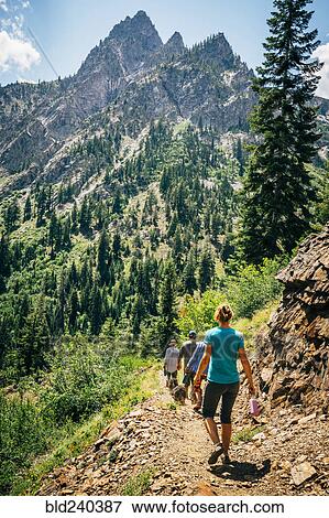 Caucasian People Hiking On Path In Mountains Stock Photo