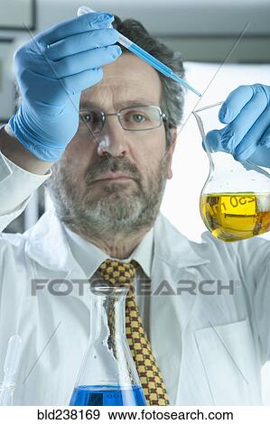 Stock Photo - Caucasian scientist mixing liquid in laboratory. Fotosearch
