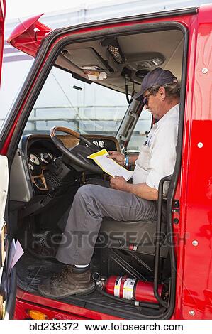 Caucasian semi-truck driver reading paperwork View Large Photo Image Stock Image - Caucasian semi-truck driver reading paperwork. Fotosearch