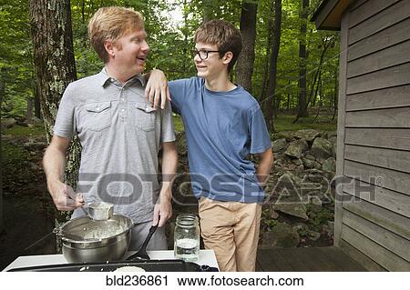 Caucasian son leaning on father cooking pancakes outdoors View Large Photo Image Stock Image - Caucasian son leaning on father cooking pancakes outdoors. Fotosearch