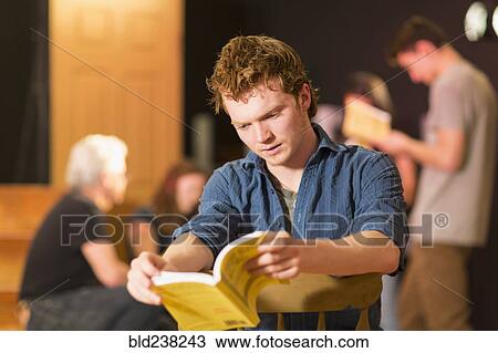 Stock Image - Caucasian teenage boy reading script in theater class. Fotosearch