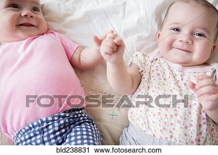 Caucasian twin baby girls smiling on bed View Large Photo Image Stock Image - Caucasian twin baby girls smiling on bed. Fotosearch