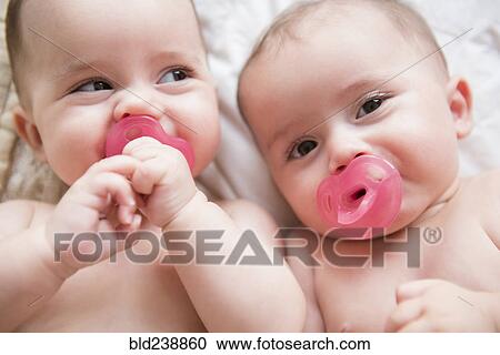 Caucasian twin baby girls sucking pacifiers View Large Photo Image Stock Image - Caucasian twin baby girls sucking pacifiers. Fotosearch