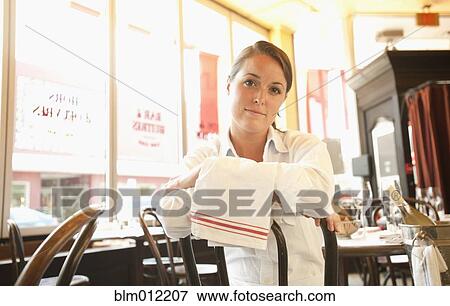 Stock Photo - Caucasian waitress sitting in restaurant. Fotosearch