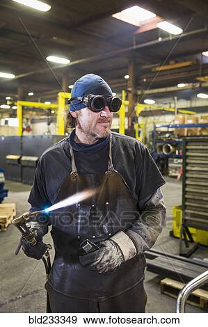 Caucasian welder holding blowtorch in factory View Large Photo Image Stock Photo - Caucasian welder holding blowtorch in factory. Fotosearch