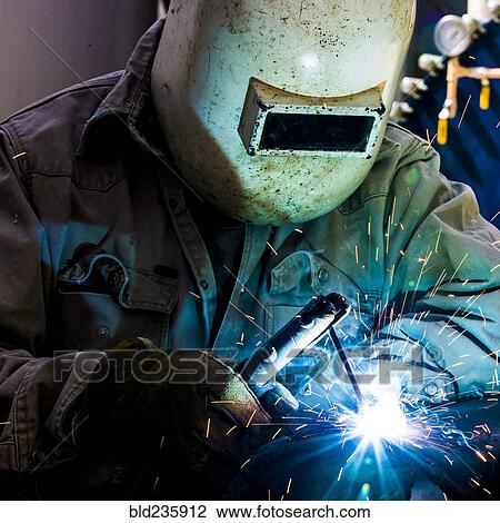 Stock Image - Caucasian welder working in factory. Fotosearch