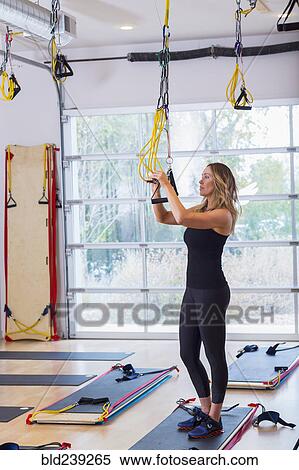 Stock Photography - Caucasian woman adjusting resistance bands in gymnasium. Fotosearch