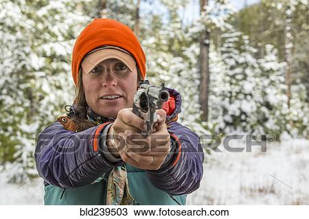 Stock Image - Caucasian woman aiming handgun in winter. Fotosearch