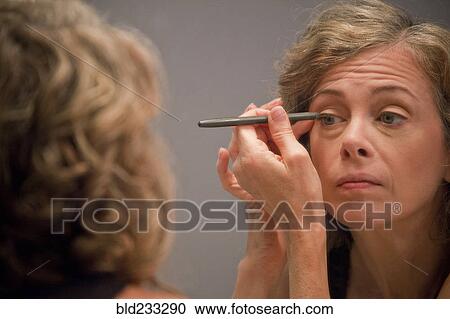 Caucasian woman applying eyeliner in mirror View Large Photo Image Stock Image - Caucasian woman applying eyeliner in mirror. Fotosearch