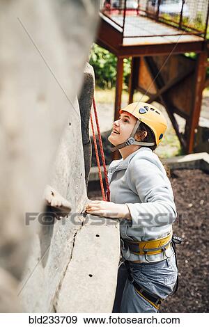 Stock Photo - Caucasian woman climbing rock climbing wall. Fotosearch