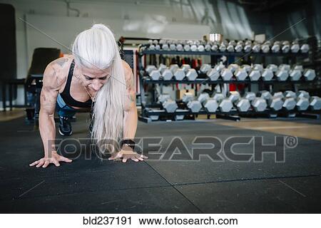 Stock Image - Caucasian woman doing push-up in gymnasium. Fotosearch