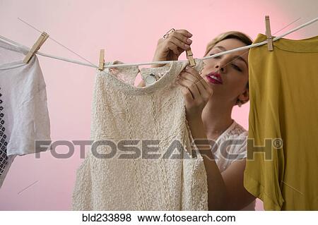 Caucasian woman hanging shirts on clothesline with clothespins View Large Photo Image Stock Photo - Caucasian woman hanging shirts on clothesline with clothespins. Fotosearch