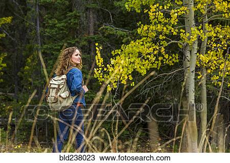 Stock Image - Caucasian woman hiking in forest. Fotosearch