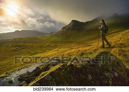 Picture - Caucasian woman hiking in green mountain landscape. Fotosearch