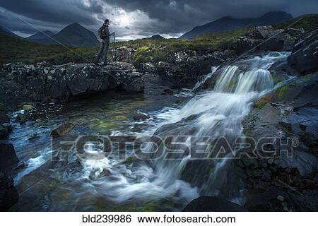 Stock Photograph - Caucasian woman hiking near river flowing over rocks. Fotosearch