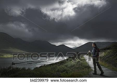 Stock Photo - Caucasian woman hiking on path near river. Fotosearch