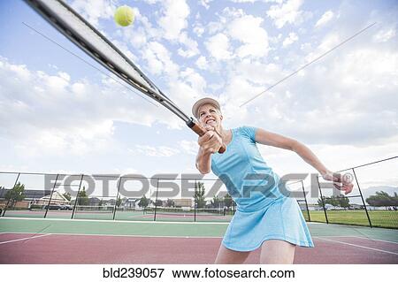 Stock Photo - Caucasian woman hitting tennis ball. Fotosearch