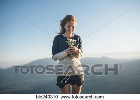 Stock Image - Caucasian woman holding bouquet of wildflowers. Fotosearch