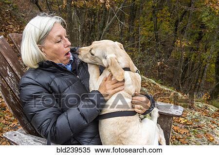 Stock Photography - Caucasian woman holding dog in lap outdoors. Fotosearch