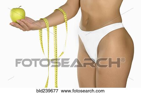 Caucasian woman holding green apple and measuring tape View Large Photo Image Stock Photo - Caucasian woman holding green apple and measuring tape. Fotosearch