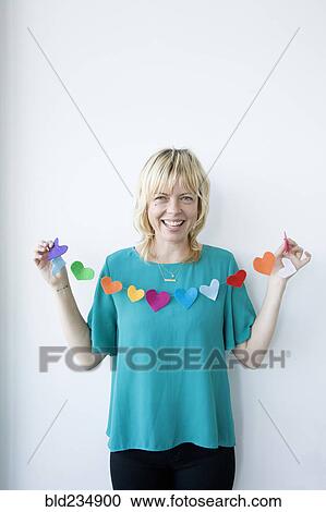 Stock Image - Caucasian woman holding string of paper hearts. Fotosearch