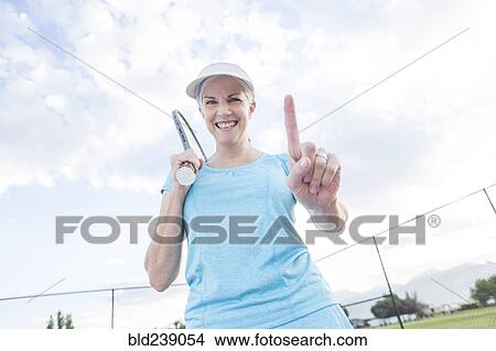 Caucasian woman holding tennis racket gesturing number one View Large Photo Image Picture - Caucasian woman holding tennis racket gesturing number one. Fotosearch