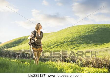 Caucasian woman holding walking stick on hill View Large Photo Image Stock Photo - Caucasian woman holding walking stick on hill. Fotosearch