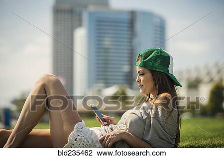 Caucasian woman laying in grass texting on cell phone View Large Photo Image Stock Image - Caucasian woman laying in grass texting on cell phone. Fotosearch