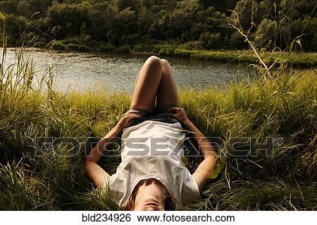 Stock Photograph - Caucasian woman laying near river. Fotosearch
